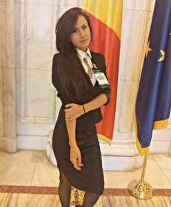 Woman in black dress standing by flags.