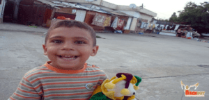 A young boy holding a stuffed animal in his hand.
