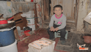 A boy sitting on a stool in front of a box.
