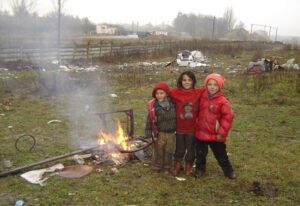 Three children standing in front of a fire.