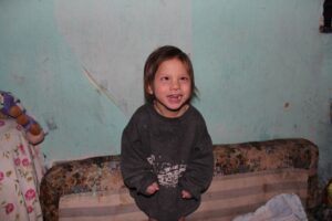 A young child standing in front of a wall.