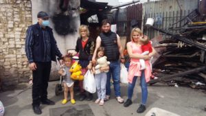 Family standing in front of a fire-damaged building.