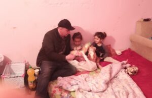 A man and two girls sitting on top of a bed.