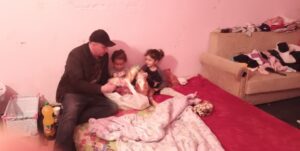 A man and two children sitting on the bed