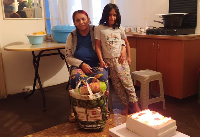A woman and child standing next to a basket of food.