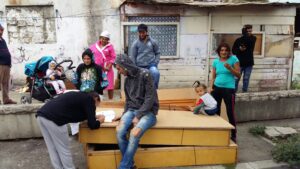 A group of people standing around on top of a wooden bench.
