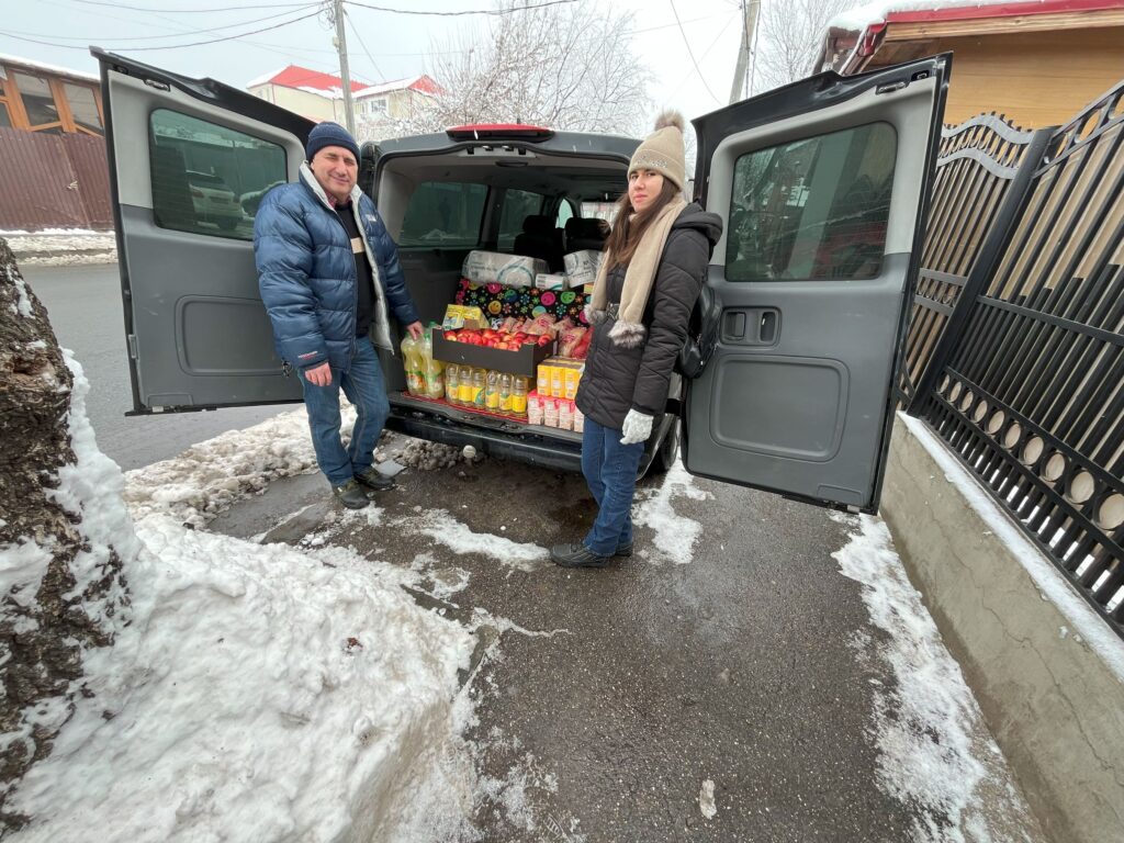 Two men standing in the back of a van with boxes.