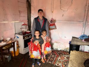 Man and two children with gifts in a home.
