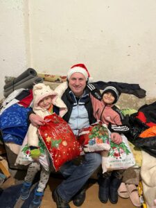 Man and two children celebrate with gifts.