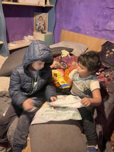 Two children exploring a plastic bag's contents.