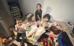 Children sitting on a bed with bags.