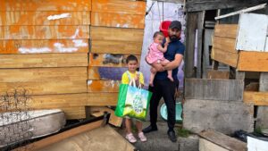 Man with children outside wooden structure.
