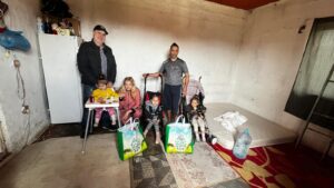 Family in a room with groceries and children.