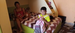 Child with backpack sitting on bed.