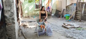 Woman and child outside in rustic yard.