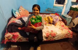 Girl sitting on bed holding gift bag.