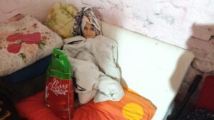 Child wrapped in blanket, smiling on bed.