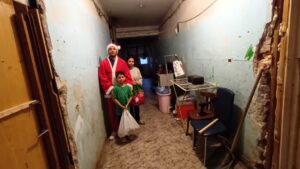Man in Santa outfit with family indoors.